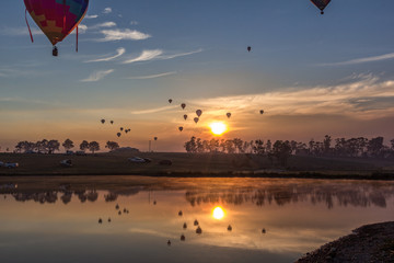 Hot air balloons taking off over lake