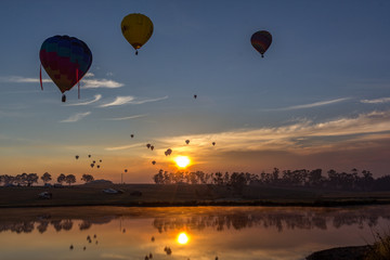 Hot air balloons taking off over lake
