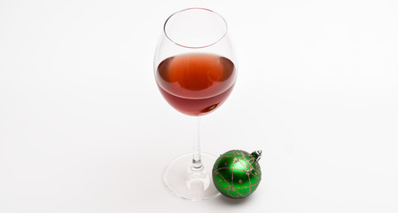 Glass with wine and christmas decoration. Christmas menu concept. Winter celebration with alcohol drink. Wineglass with red liquid or wine and christmas ball ornament isolated on white background