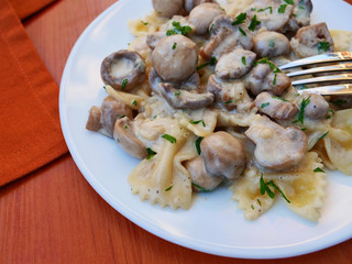 Farfalle pasta in creamy mushroom sauce on white plate closeup