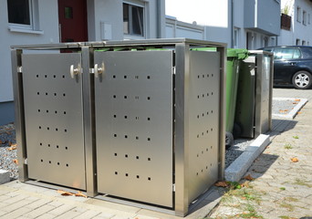 Stationäre Einhausung von Abfall-Sammelbehältern als Sichtschutz vor Wohnhäusern im Neubaugebiet