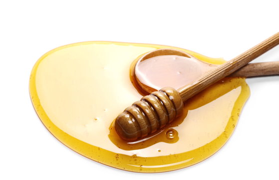 Honey with wooden dipper and spoon isolated on white background