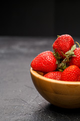 Photo close-up of ripe strawberry in wooden cup on black background