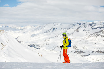 Photo of sportive man skiing against background of snowy mountains