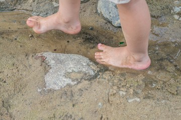 Kleiner Junge steht mit seinen Füßen in einer Wasserpfütze