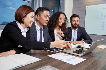 Young multiethnic men and women using laptop at table in office having business meeting