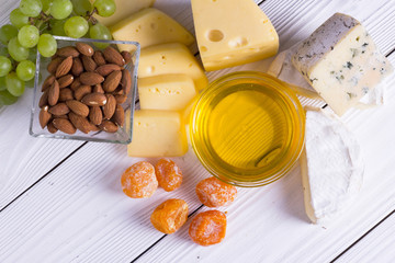 Wine with snacks - various types of cheese, figs, nuts, honey, grapes on a wooden boards background