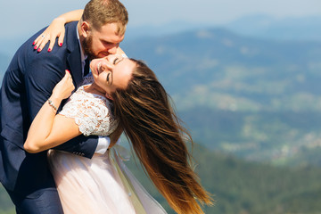 sensual hugs of newlyweds and cute smiles against the background of the mountains. the wind blowing on her hair.