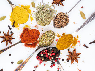 Set of spices in spoons on white background, top view. Paprika, curry, Bay leaf, anise and other seasonings, flat lay