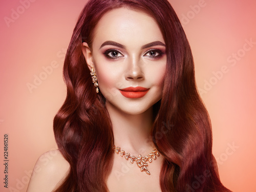 Brunette Girl with Long Healthy and Shiny Curly Hair. Care and Beauty. Beautiful Model Woman with Wavy Hairstyle. Make-Up and Jewelry