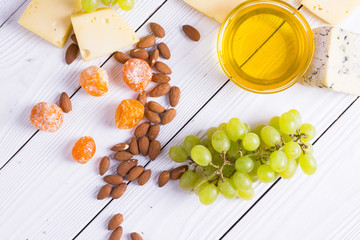 Cheese cuts with figs, nuts, honey, grapes on a wooden boards background