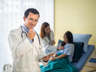 Fototapeta premium smiling male doctor wearing a stethoscope and female doctor and patient discussing something while sitting at bed background.