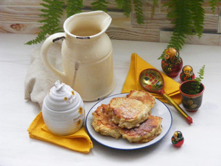 Traditional russian cuisine : pancakes on plate with oak flakes on  shabby white wooden background with rustic milk jug, honey, yellow napkins and nesting dolls matrioshka