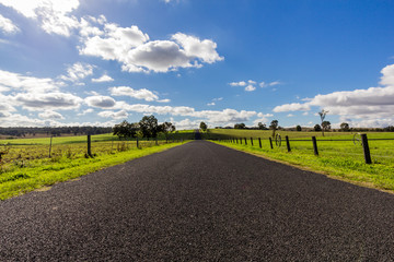 Fototapeta na wymiar Asphalt road against cloudy blue sky and green countryside