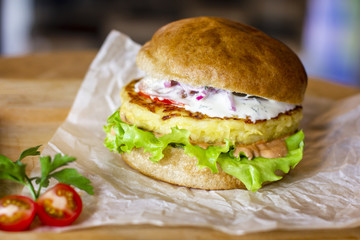 Vegetarian Burger with potato cutlet, salad and sauce on wooden Board