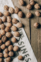 top view of whole walnuts and business newspaper on wooden table