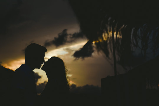 Silhouette of couple looking at each other in front of sunset in backlight.