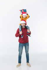 father in santa hat carrying son with christmas present on shoulders isolated on white