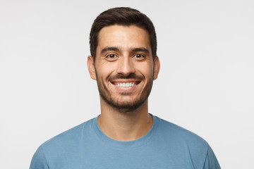 Close up portrait of smiling handsome man in blue t-shirt isolated on gray background