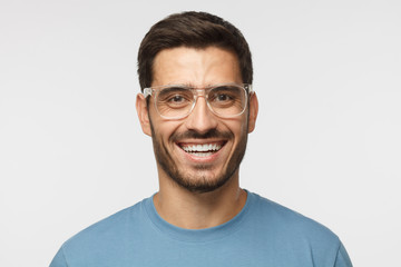Fototapeta premium Laughing out loud concept. Joyful modern young man in blue t-shirt smiles broadly, laughing, showing perfect white teeth.
