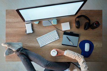 Top view of creative web designer woman making break while holding legs on the desk.