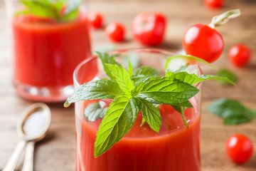 Tomato juice with mint in glass and fresh tomatoes on a wooden table. Healthy organic food concept