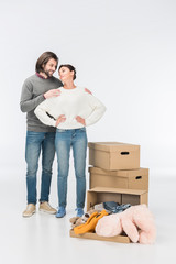 couple standing near carton box with toys and looking at each other isolated on white