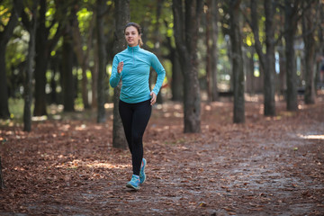  A beautiful girl in sportswear is running around in the park in the fall.