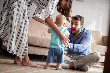 happy mother and father playing with a baby at home.