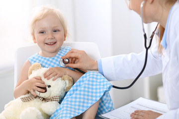 Doctor examining a little blonde girl with stethoscope.Medicine and healthcare concept