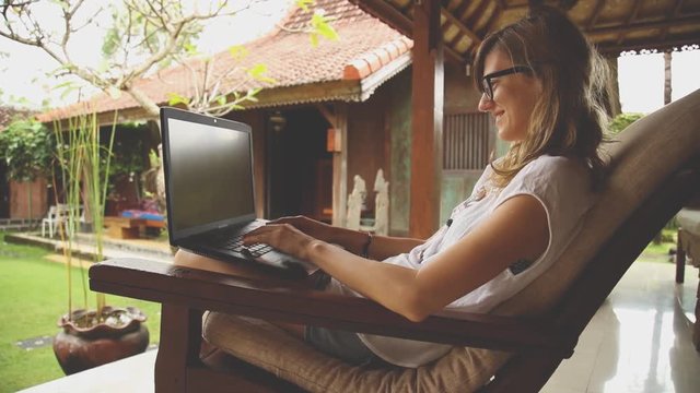 Girl using laptop on the garden porch.