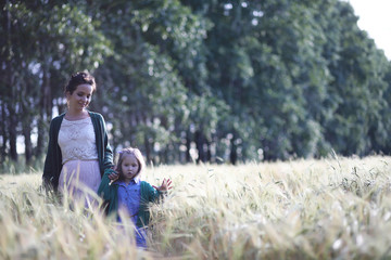 Naklejka na ściany i meble A young mother walk in wheat fields