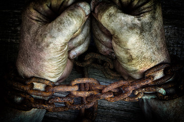 Dirty male hands clenched into fists chained with rusty chain