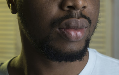 Obraz premium Male lips close up, jalousie background. African peoples beauty concept. Lips of Black macho with beard. Sensual big lips of bearded african macho