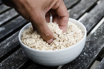 man grabbing some rolled oats from a bowl.