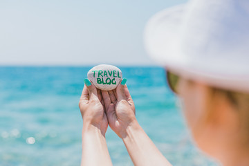Girl holding pebble stone with sign about travel theme. My travel blog. Traveling blog. Sea holidays. Sea pebbles on the sea background