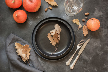 Thanksgiving Day or Halloween place setting with pumpkin on black table. Top view.