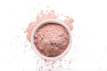 Dry pink clay powder mask for face and body  in ceramic bowl isolated on white