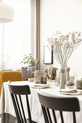 Close-up of chairs and table with flower and tableware in a dining room interior. Real photo