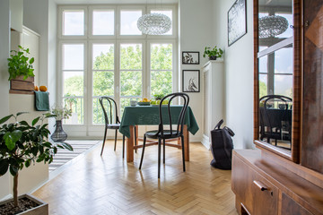 Real photo of a table with green cloth, chairs and close-up of a cupboard in a retro dining room interior