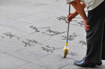 Man writing calligraphy on the ground, Beijing, China.