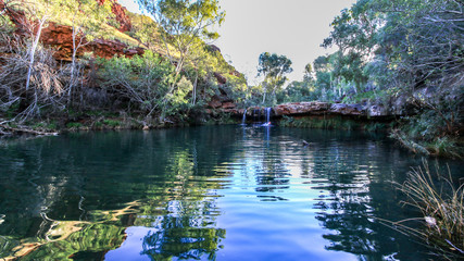 Waterfall and natural pool surrounded by red rock and trees