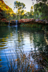 Waterfall and natural pool surrounded by red rock and trees