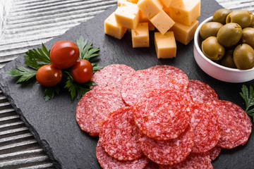 delicious sliced salami on a stone plate wooden background
