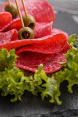 delicious sliced salami on a stone plate wooden background