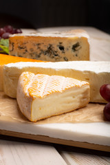 Tasting plate with four France cheeses, cream brie, marcaire, saint paulin and blue auvergne cheese, served with fresh ripe grapes