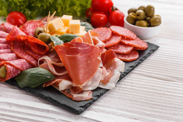 Cold smoked meat plate on a rustic wooden background