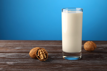 A glass of milk with walnuts on a blue background.
