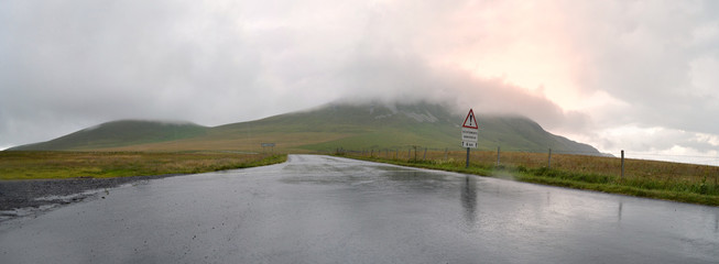A dangerous mountain road under a storm cloud and rain