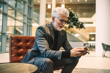 Senior executive using phone in office lobby